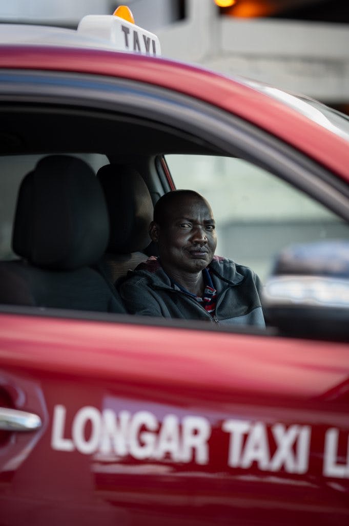 A taxi driver sits in his cab.