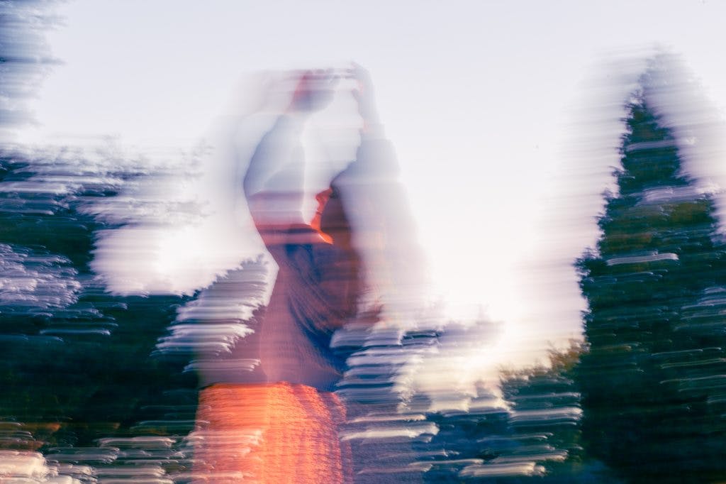 Girl dancing in a blur of light surrounded by trees