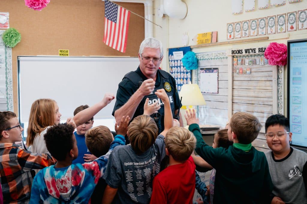 Officer Martin Knaul fist-bumps students at Harry E. Elden Elementary school following an active shooter drill. He came out of retirement to build lasting relationships with the kids and hopes to leave an impact on the next generation. “I missed the kids; I enjoy the interactions and I aways hope to make some kind of impact or influence for the kids to make better choices in life.”